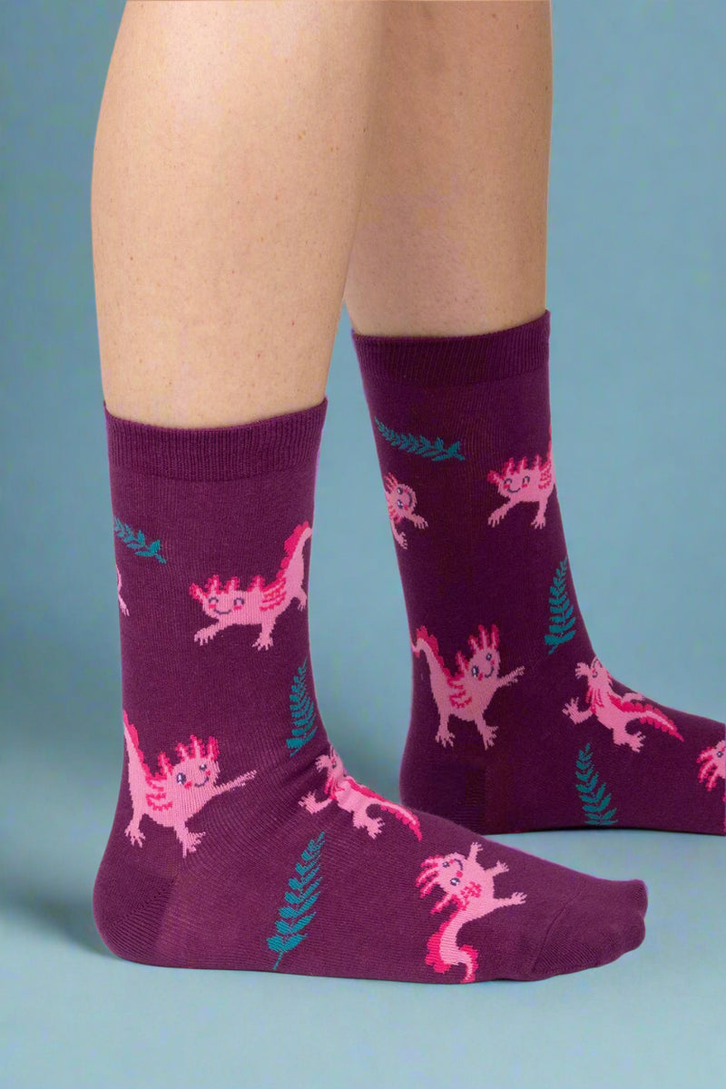 Purple socks with pink dinosaur pattern worn by a person on a white background