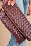 Model is holding a quilted fold-over wristlet clutch with zipper closure. 
