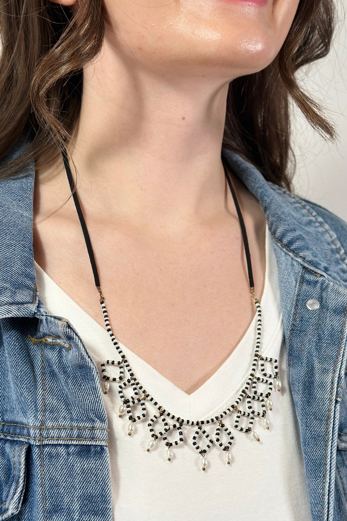 Model is wearing a black and white beaded necklace. 