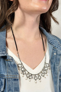 Model is wearing a black and white beaded necklace. 