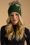 Woman wearing a green knit beanie with a pom-pom on a gray background