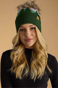 Woman wearing a green knit beanie with a pom-pom on a gray background