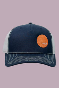 Navy colored trucker hat with white mesh back and contrasting stitching, featuring an embroidered Spot logo.
