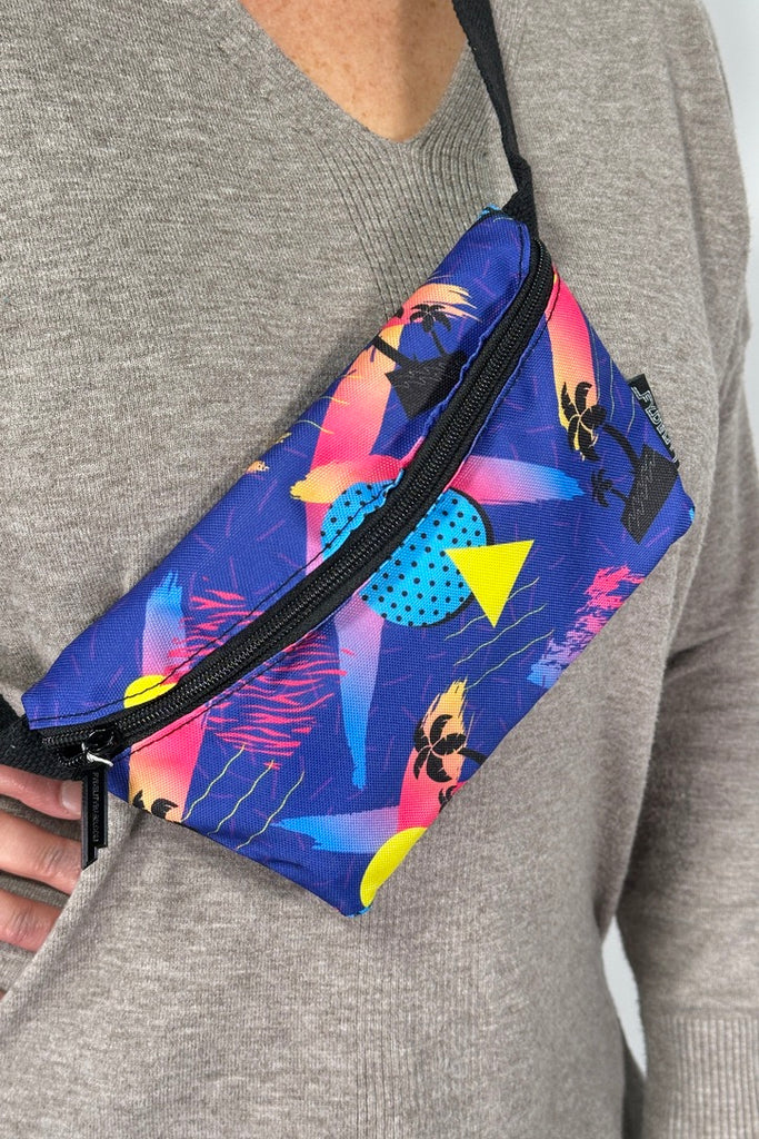 Model is wearing a n 80's ocean inspired printed fanny pack bag with an adjustable canvas strap. 