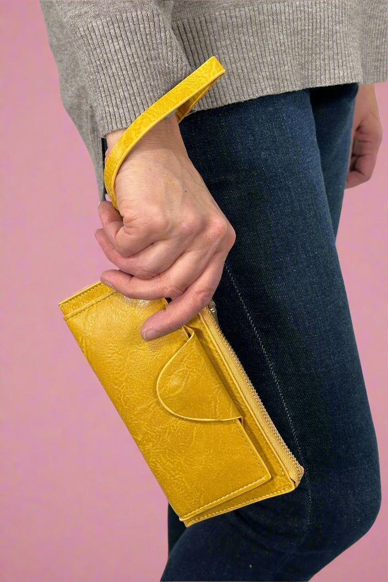 Model is holding a yellow colored wallet that doubles as a wristlet. 