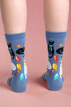Blue socks with cat and balloon design worn by a person on a white background