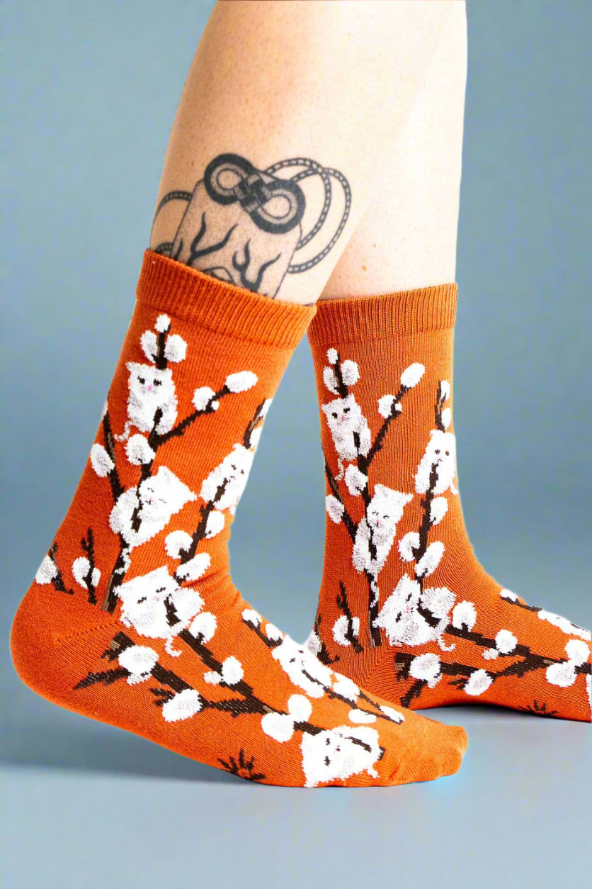 Orange socks with white floral design worn by a person on a white background