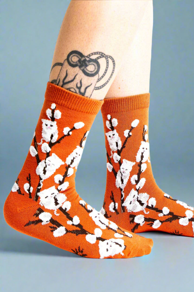 Orange socks with white floral design worn by a person on a white background