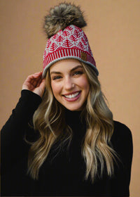 Woman wearing a red and white patterned knit hat with a pom-pom on a dark background