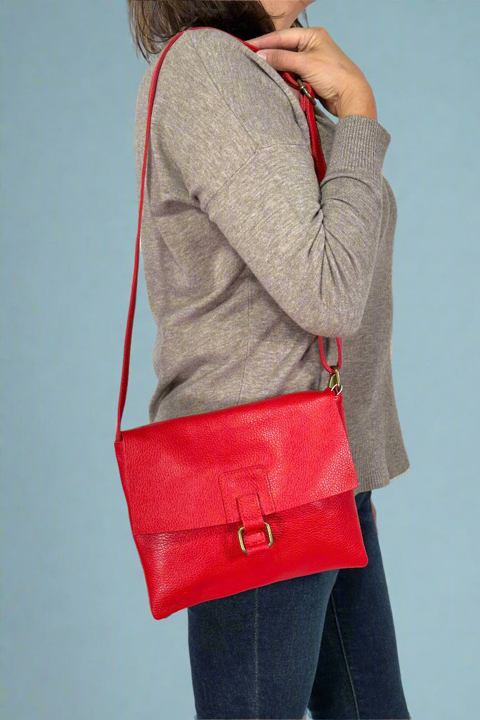 Model is wearing a red colored leather flap crossbody bag.