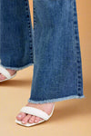 Close-up of blue jeans with a white sandal on a light background.