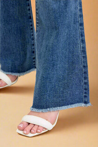Close-up of blue jeans with a white sandal on a light background.