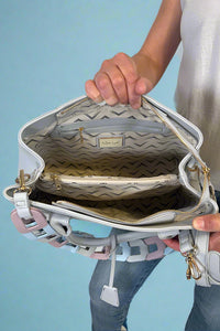 Model is carrying a large satchel with removable colorful woven strap. 