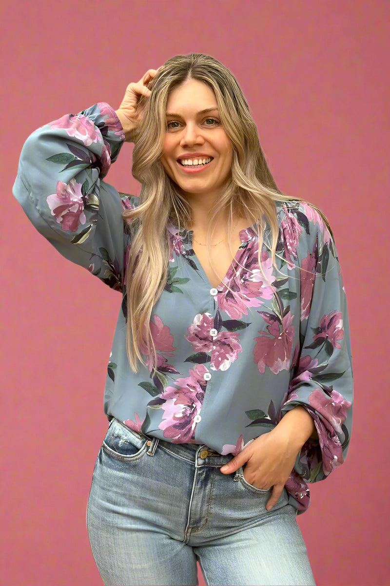 A soft grey and floral blouse. With a slit v-neck, long cinched sleeves, and faux buttons. 
