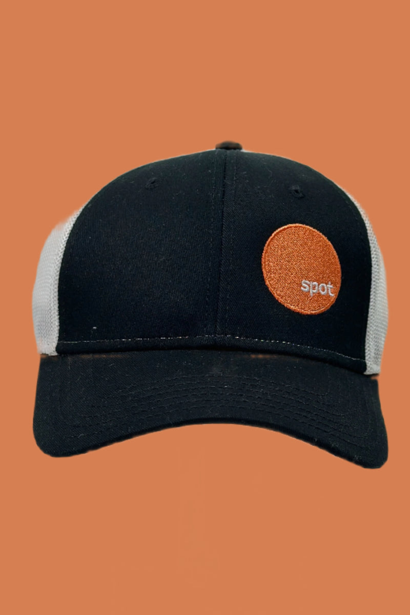 Black trucker hat with a contrasting white mesh back featuring an embroidered Spot logo.