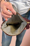 Model is holding a quilted fold-over wristlet clutch with zipper closure. 