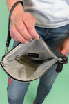 Model is holding a quilted fold-over wristlet clutch with zipper closure. 