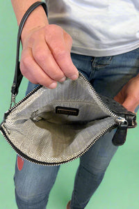 Model is holding a quilted fold-over wristlet clutch with zipper closure. 