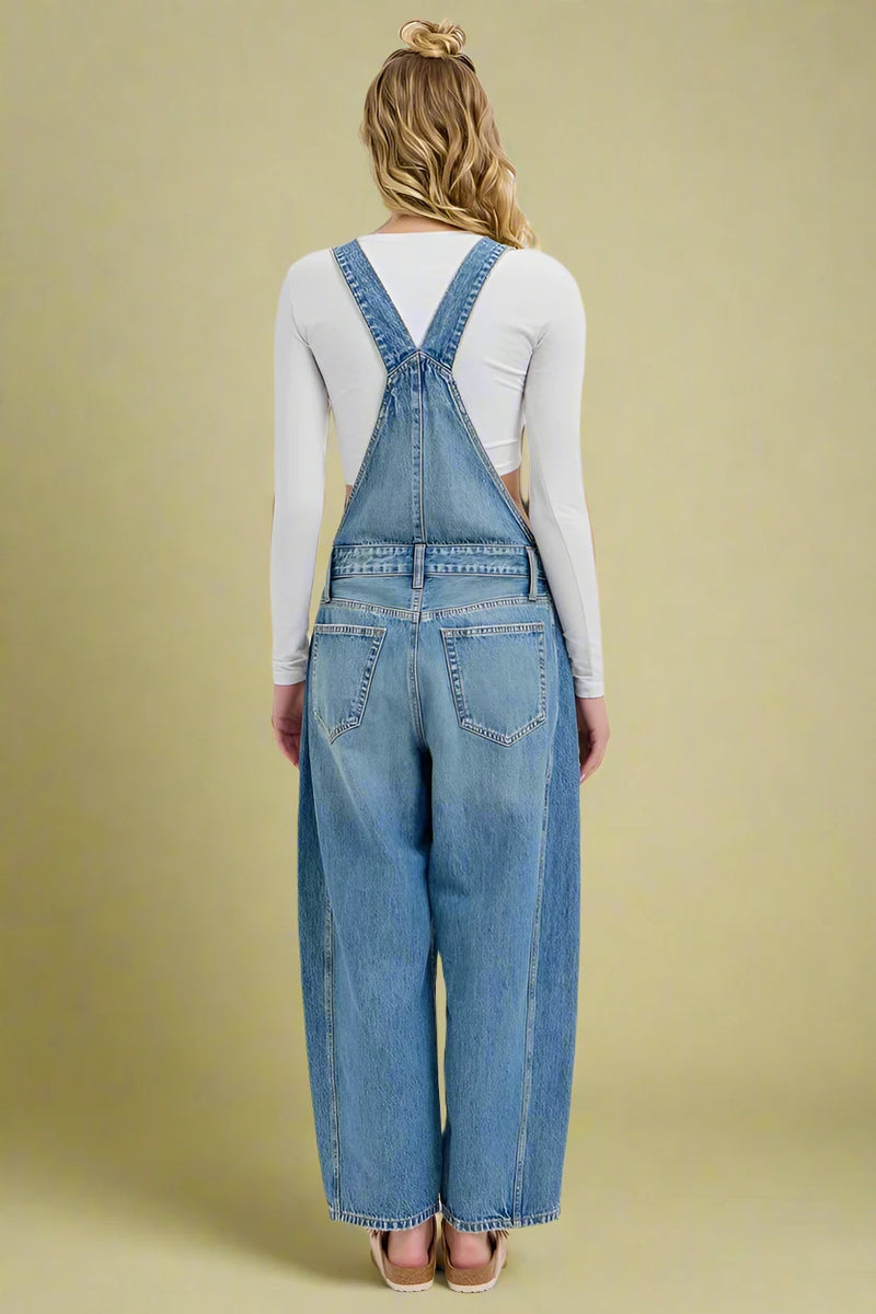 Person wearing blue denim overalls on a white background
