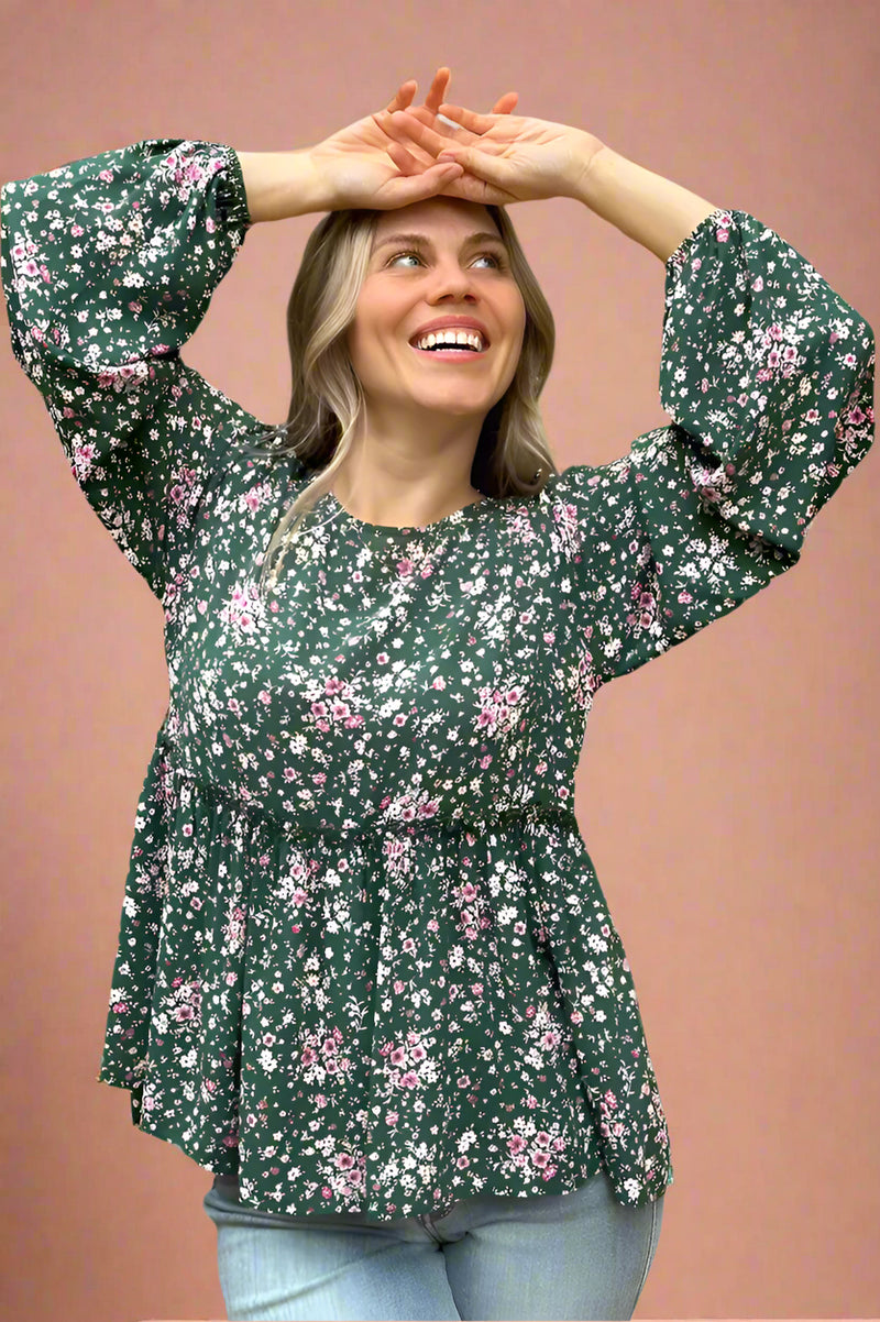 A green peplum top with a pink floral pattern. It has long sleeves that are cinched at the wrist. 
