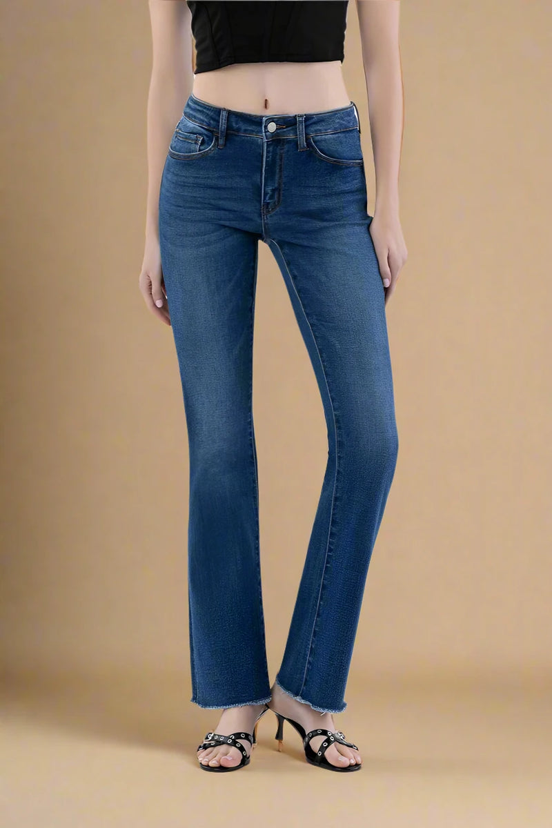 Person wearing dark blue bootcut jeans on a plain background.