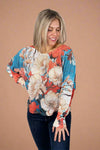 Model is wearing a thin knit sweater with dolman sleeves and a vibrant floral pattern.