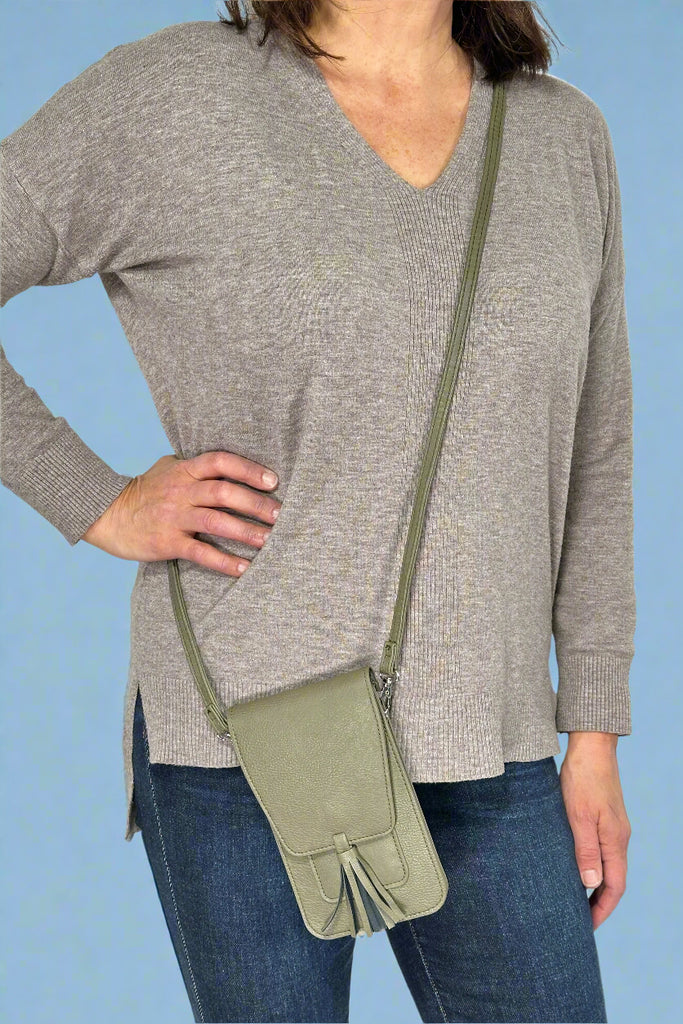 Model is wearing an army green colored mini crossbody bag with a small tassel.