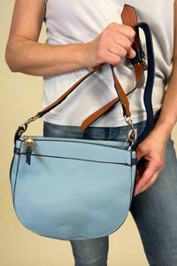Model is carrying a blue color block cross body bag. 