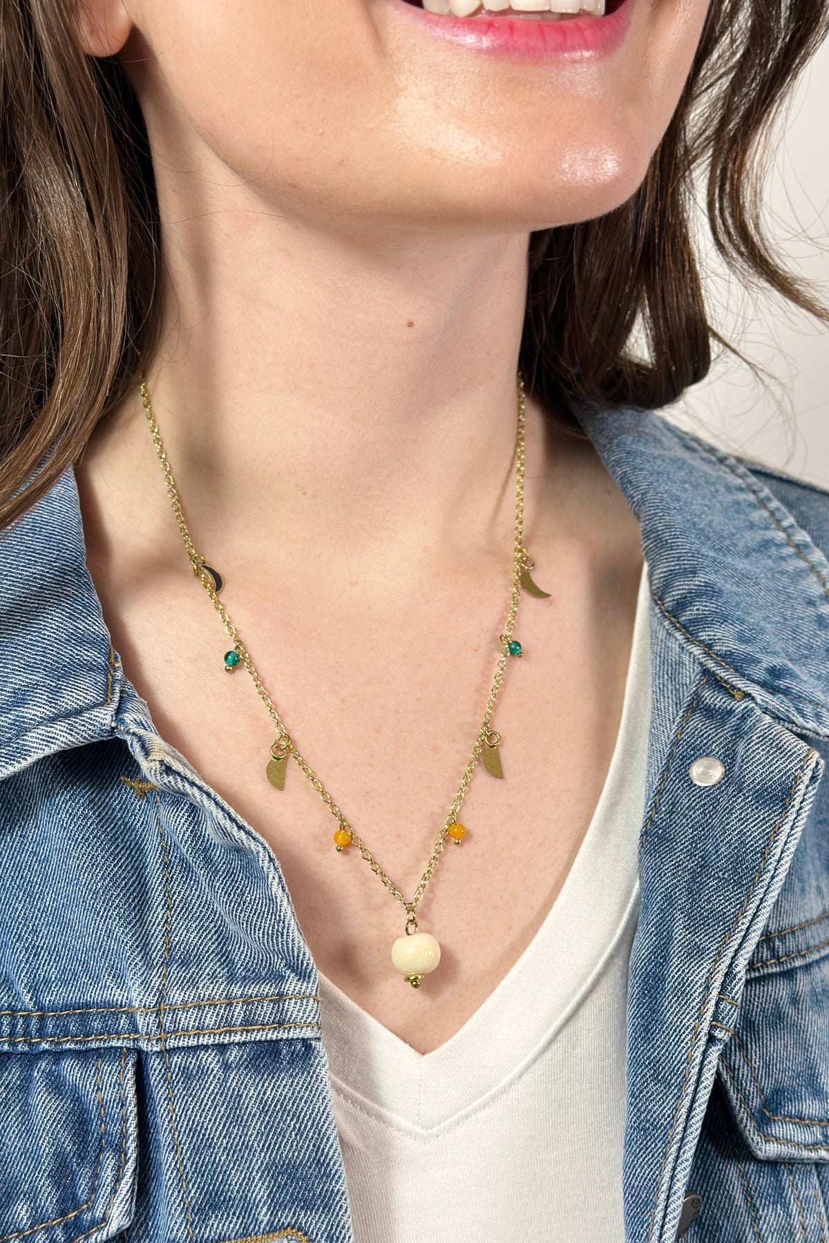 Model is wearing a gold necklace with varied celestial charms. 