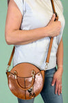 Model is carrying a small circle purse with braided handle, gold keychain and exterior pockets. Includes a cross body strap. 
