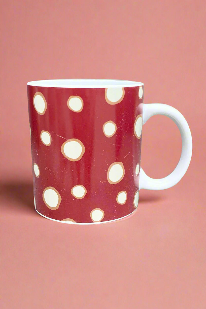 A classic coffee mug with red mushroom cap print covering it all.