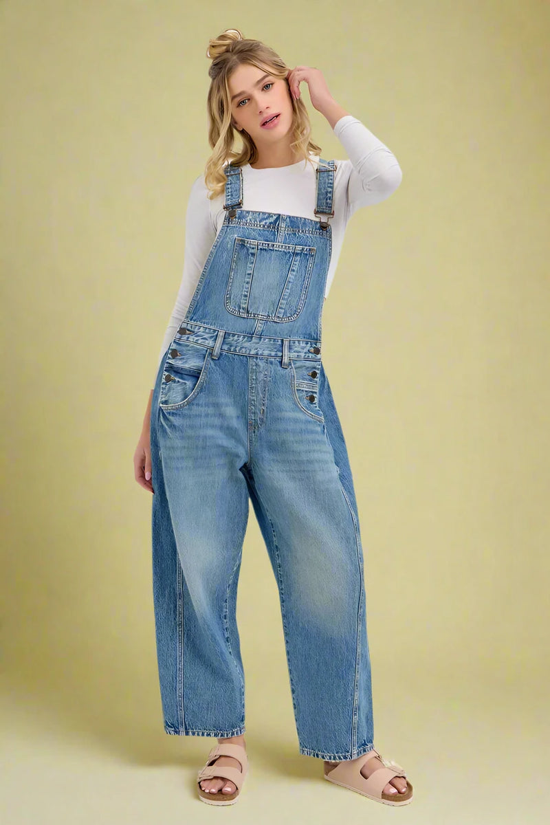 Woman wearing blue denim barrel leg overalls on a white background