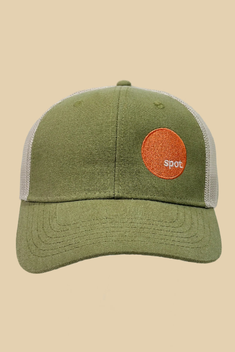 Sage green colored trucker hat with cream mesh back featuring an embroidered Spot logo. 