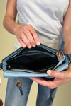 Model is carrying a blue color block cross body bag. 