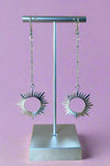 Long silver dangly earrings with a sun inspired pendant. 