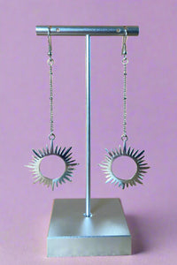 Long silver dangly earrings with a sun inspired pendant. 