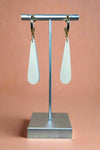 A pair of white and gold dangle earrings.