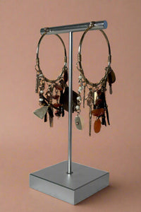 Boho style gold hoop earrings that feature an array of charms and stones dangling.