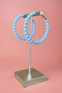 Matte light blue colored beaded hoop earrings.