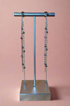 Long Silver colored dangly earrings with thin chain strands that feature small silver beads. 