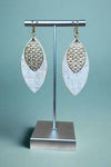 A pair of white cork and gold dangle earrings.