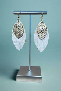 A pair of white cork and gold dangle earrings.
