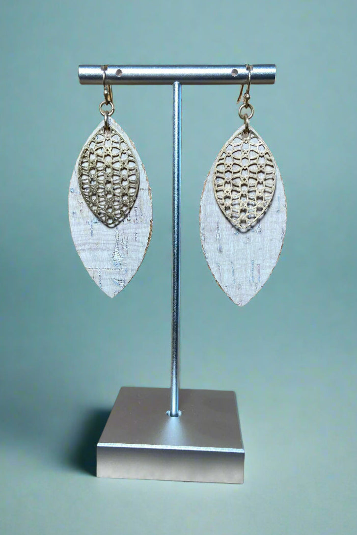 A pair of white cork and gold dangle earrings.