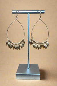 These gold earrings feature a teardrop shape and fringe beads.