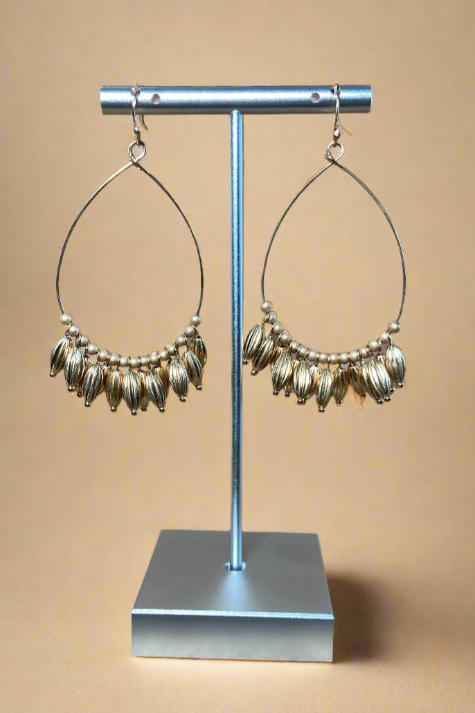 These gold earrings feature a teardrop shape and fringe beads.