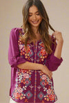 A womens lightweight blouse in fuchsia featuring a floral embroidered front, rolled 3/4 sleeves, and split neckline.