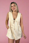 Model is wearing a pintuck detailed cream romper with pockets and a side zipper for entry.
