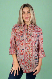 Model is wearing a lightweight pink floral western inspired top with snap buttons.