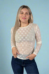 Model is wearing a sheer fitted white crew neck long sleeve that features a shimmery repeating bow pattern.