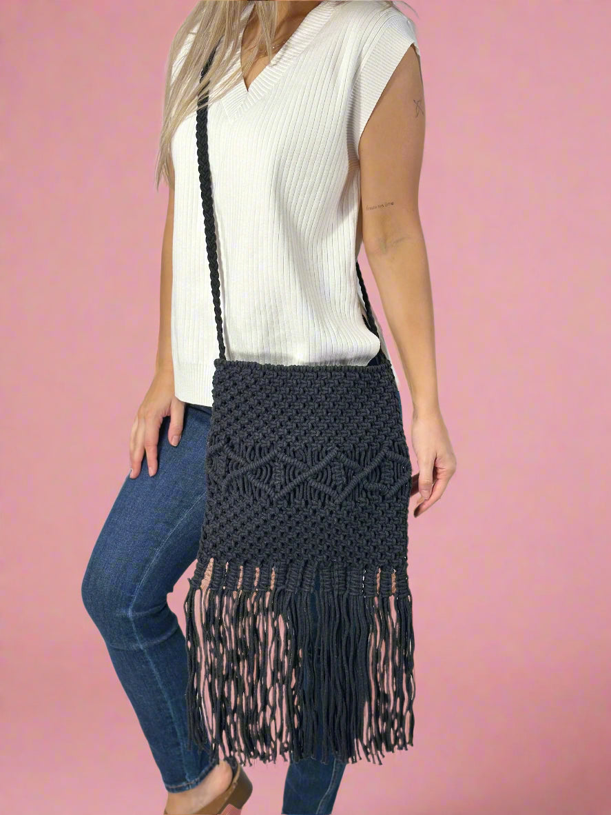 Model wearing a black cotton macrame crossbody bag with fringe detailing. 